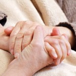 Younger person holding elderly person's hand.