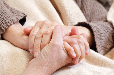 Younger person holding elderly person's hand.